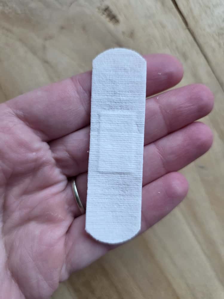 Katoenen pleister in een hand, met het wondkussentje zichtbaar