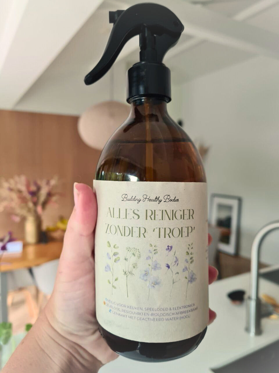 Amberglazen BHB allesreinigerfles met zwarte spraykop, in de hand gehouden