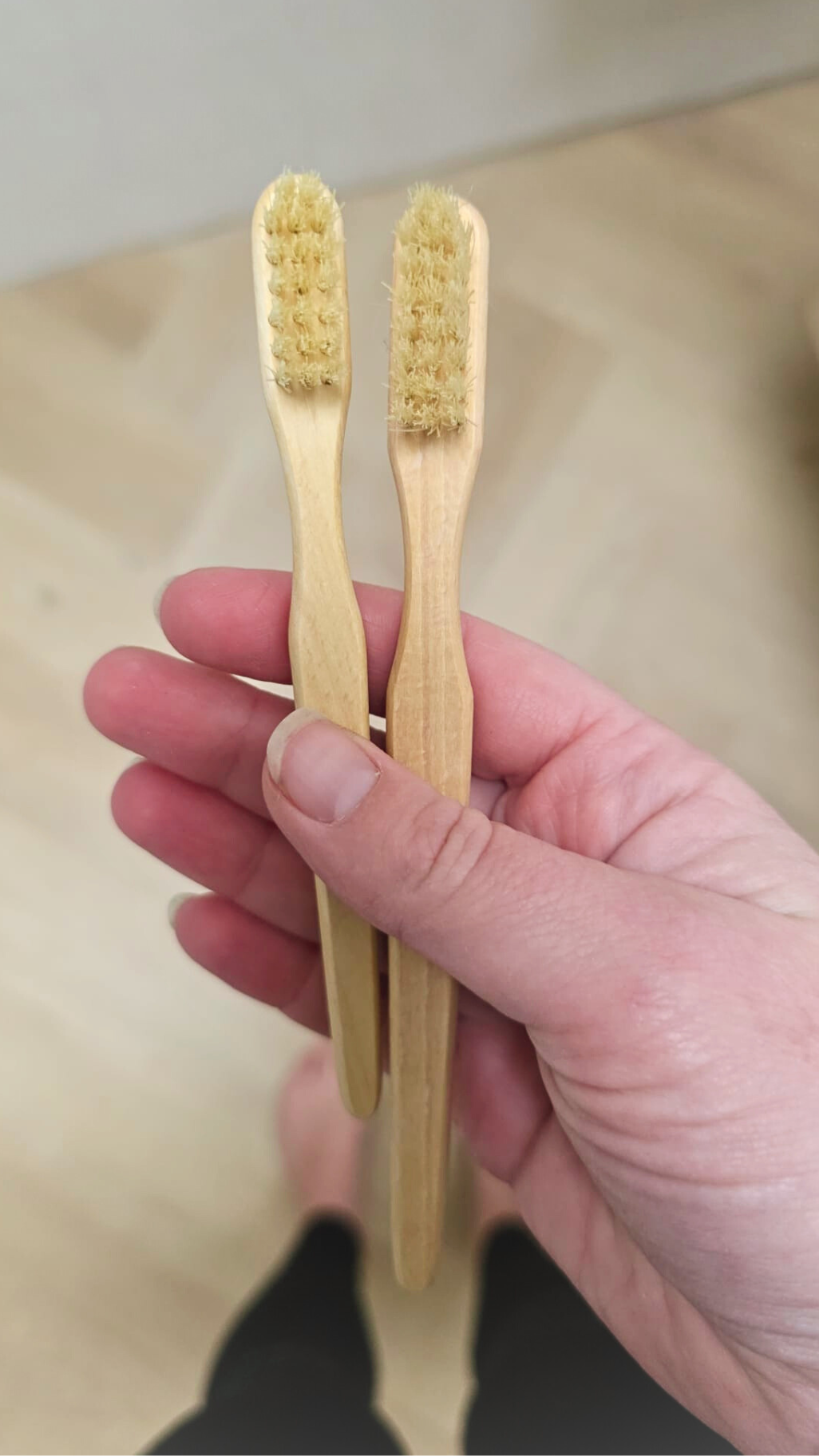 Twee houten tandenborstels in verschillende formaten in een hand