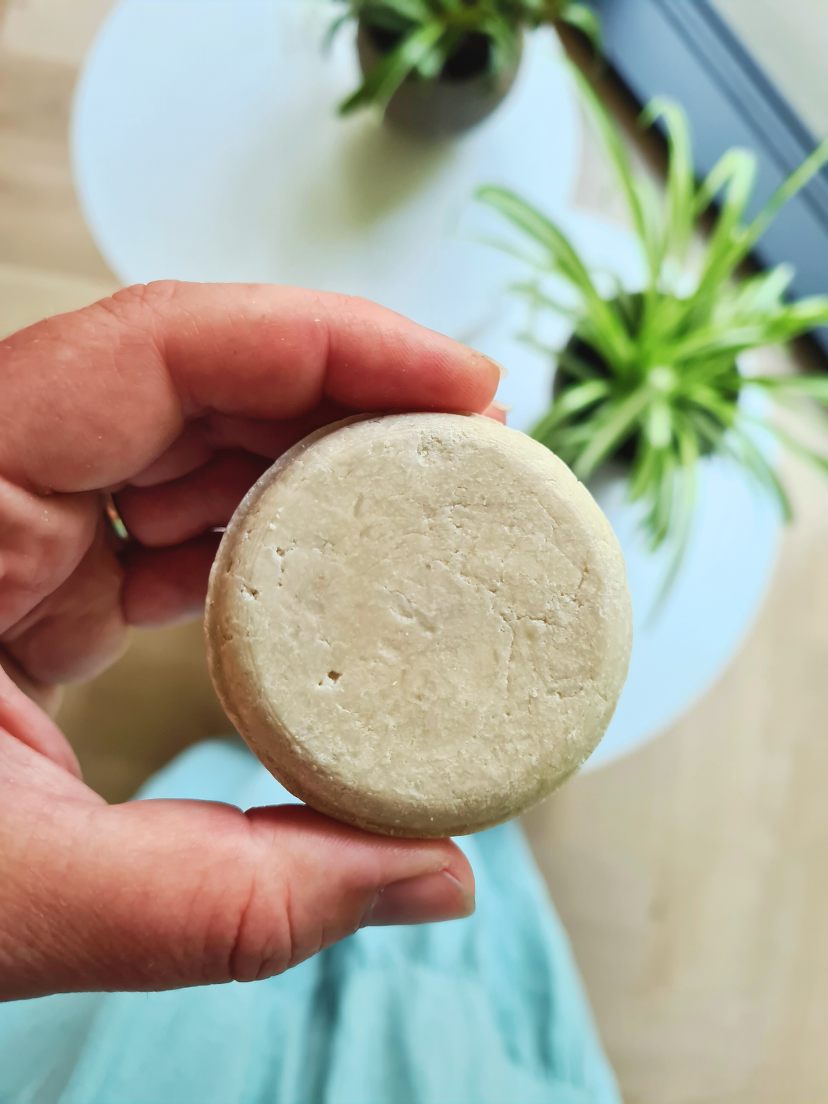 Ronde, lichte BHB shampoobar in de hand