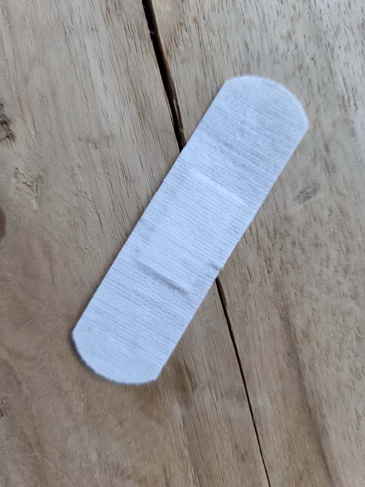 Witte katoenen pleister met afgeronde uiteinden op een houten tafel